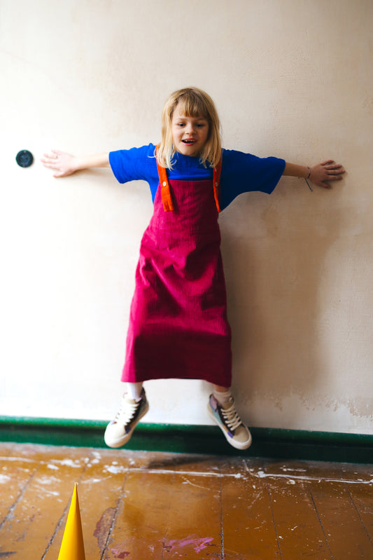 różowa spódniczka ogrodniczka z pomarańczowymi szelkami